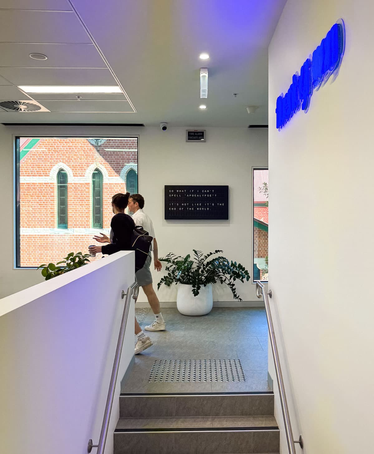 The stairwell inside the Brisbane office, with the neon lockup on the wall