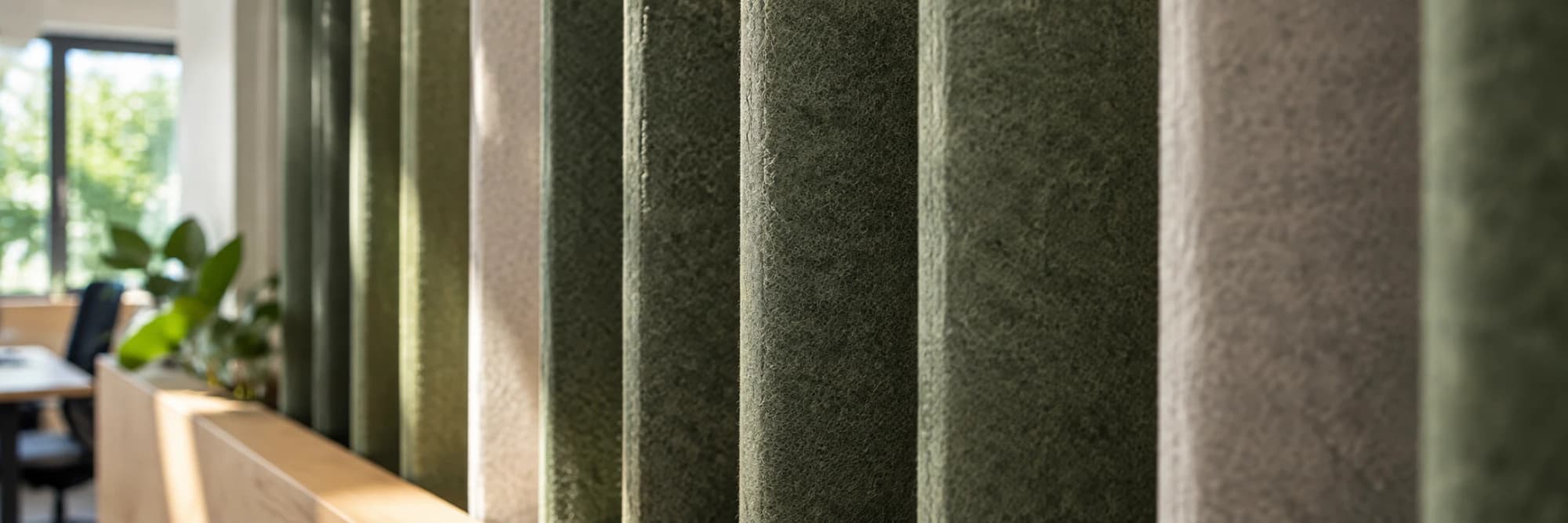 A run of felt acoustic panels in greens and greys, one in sharp focus