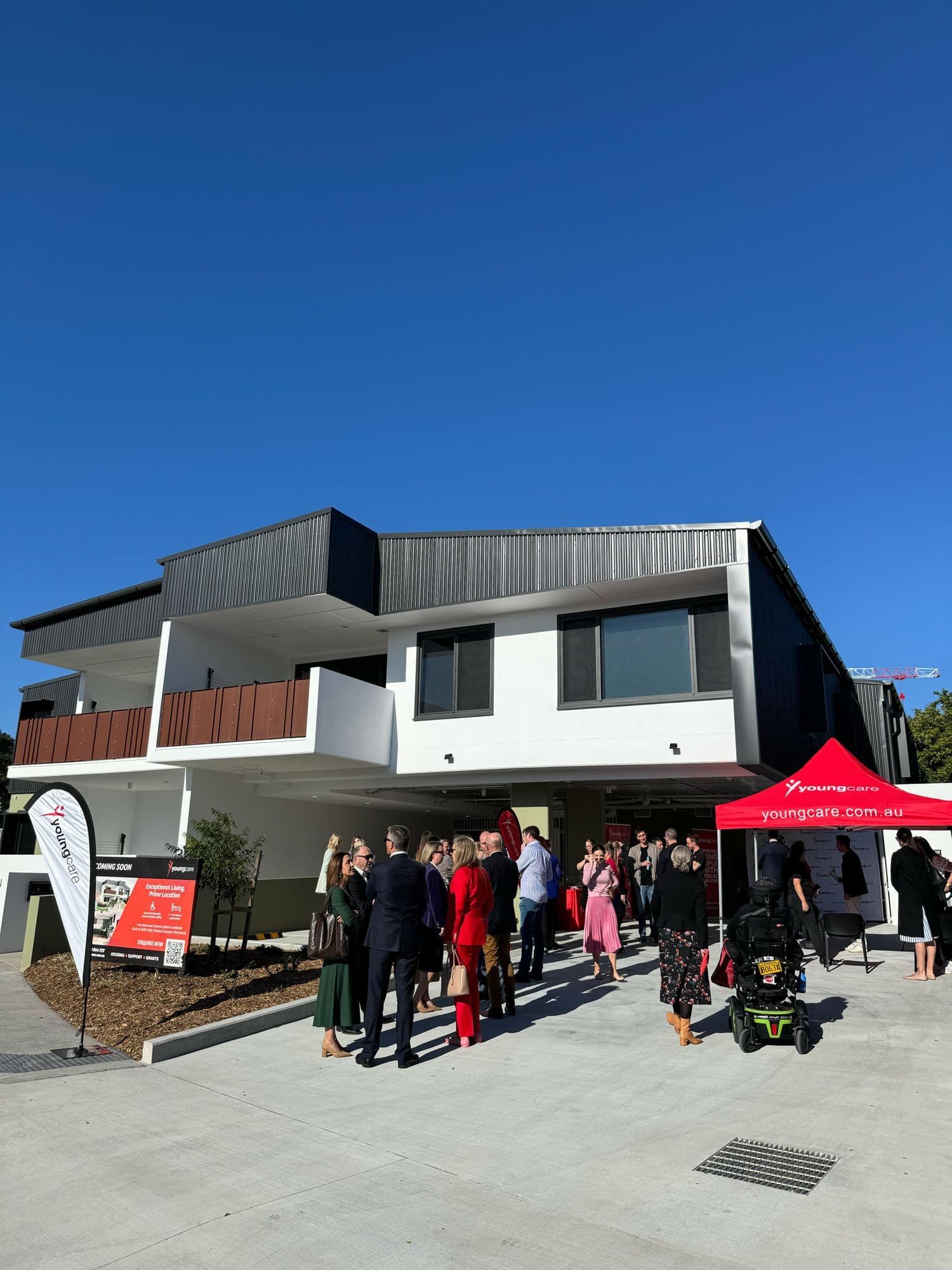 Supporters gathered outside a new Youngcare home on its opening day, a Youngcare marquee and banner by the entrance