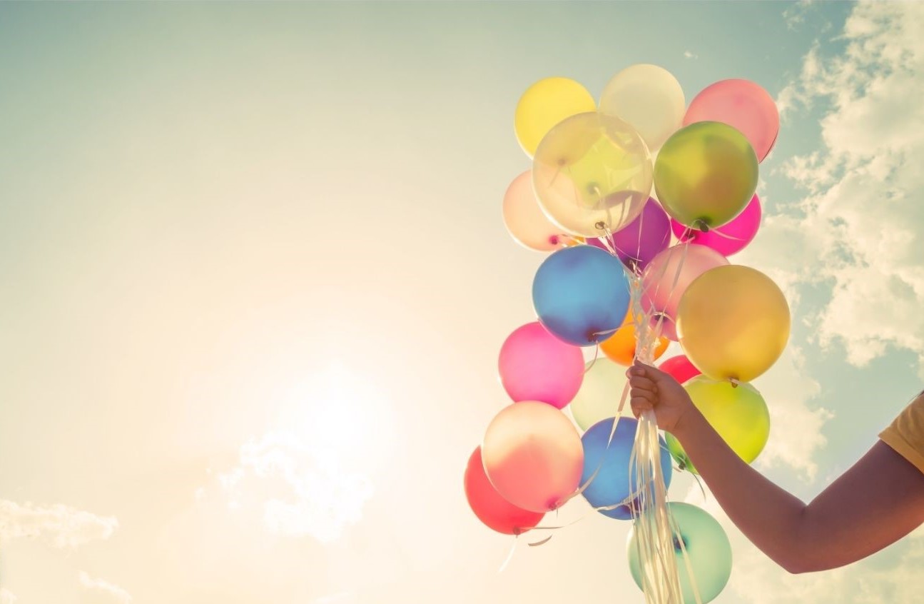 a hand holding many colourful balloons