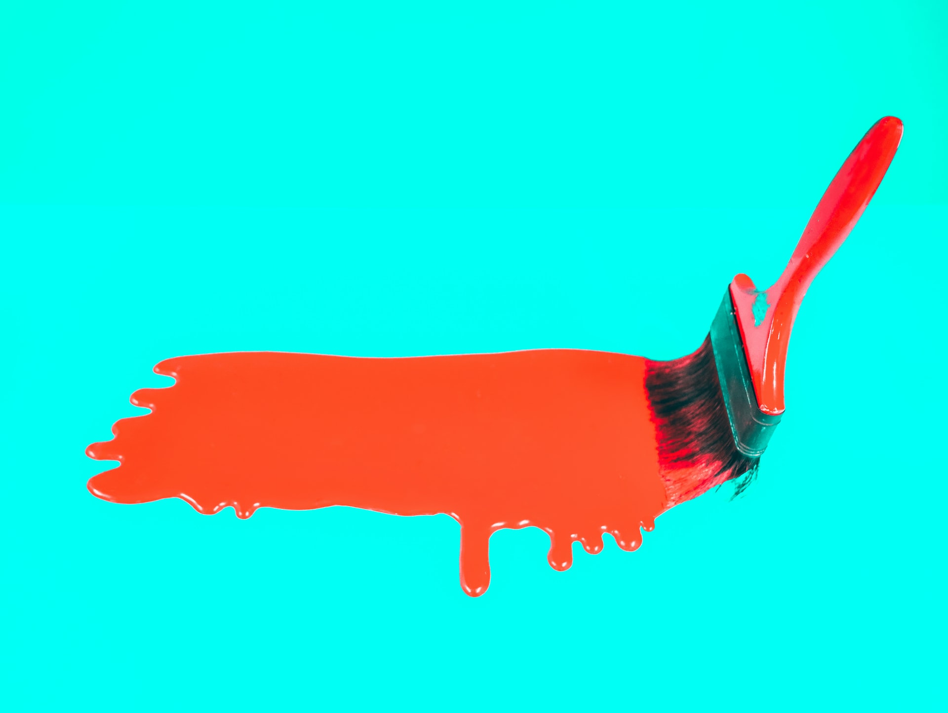 paint brush painting red on a cyan background