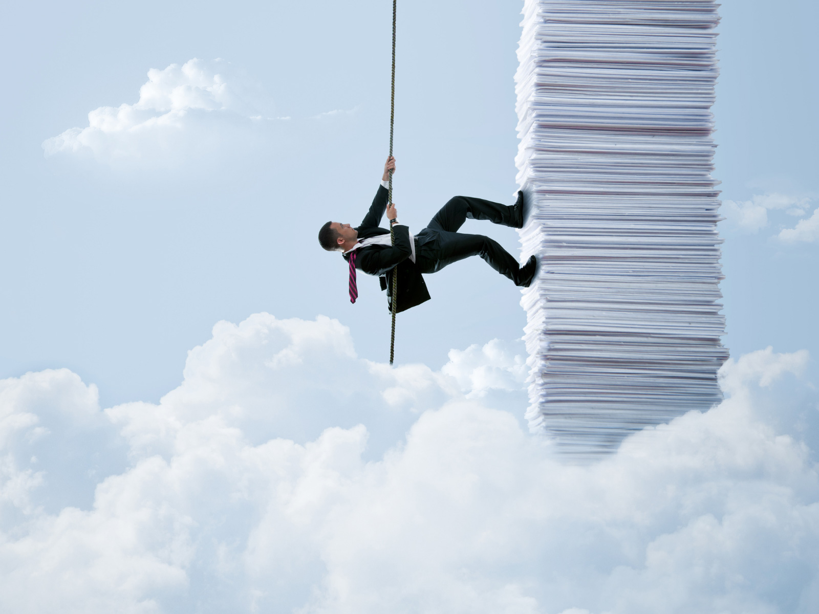 Man in a suit scaling up a stack of paper