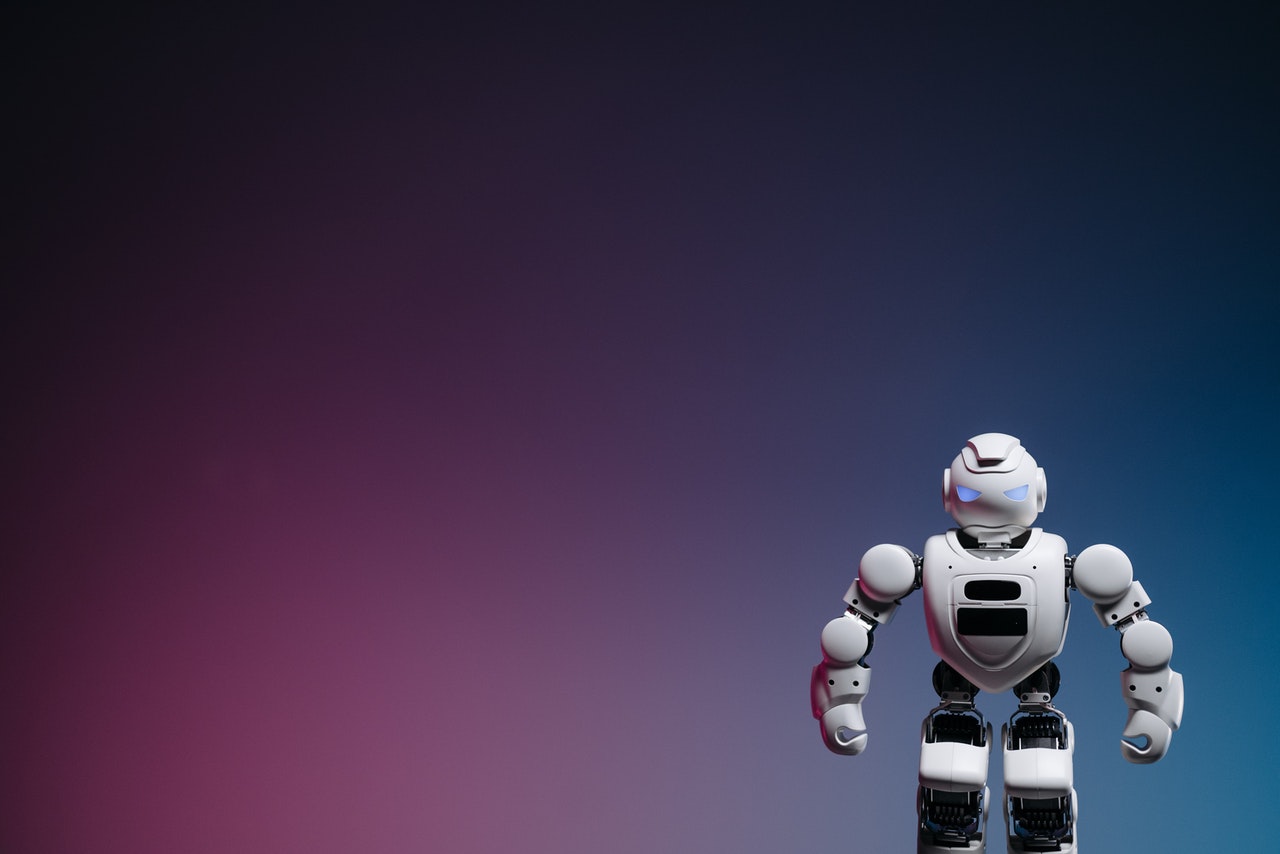 White toy robot standing in front of a gradient background